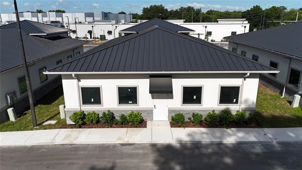 An aerial view shows the exterior of a modern, single-story commercial building with a metal roof — 2625 OCOEE APOPKA ROAD UNIT 7, APOPKA, FL