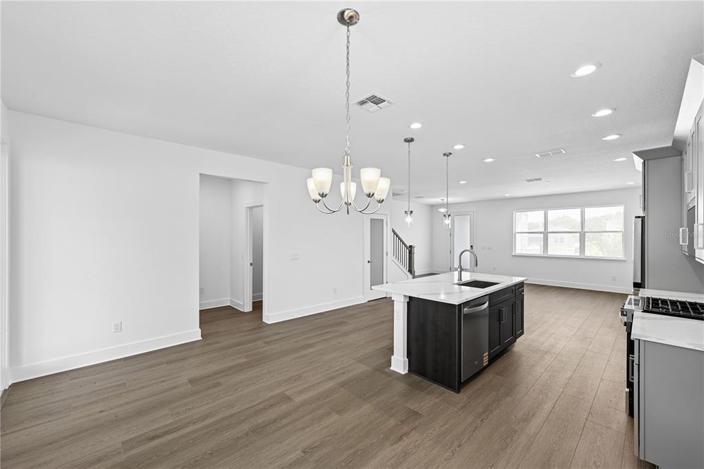 A modern kitchen features a dark island, white cabinetry, and light wood-look flooring — 1582 RIDGEBACK DRIVE, APOPKA, FL