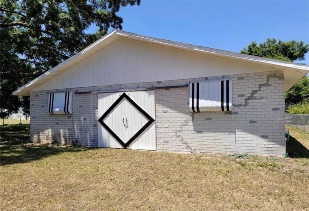 A white brick building with a sliding barn door and striped window awnings — 1910 LITHIA PINECREST ROAD, VALRICO, FL