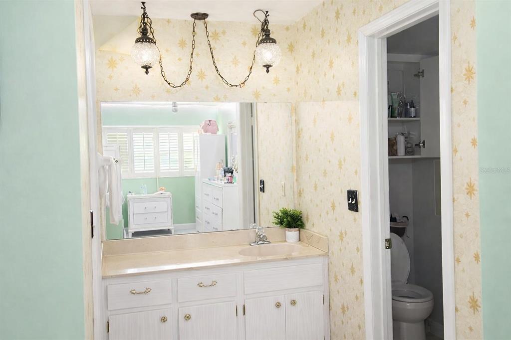 A bathroom features a white vanity, a large mirror, and yellow star-patterned wallpaper — 1910 LITHIA PINECREST ROAD, VALRICO, FL