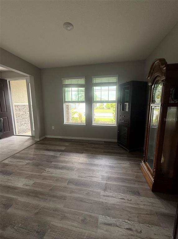 A room with wood-look flooring, two windows, and a grandfather clock near the entrance — 17625 CANTARINA COVE, BRADENTON, FL