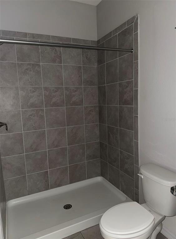 A bathroom features a white shower base, gray tiled walls, and a white toilet — 17625 CANTARINA COVE, BRADENTON, FL