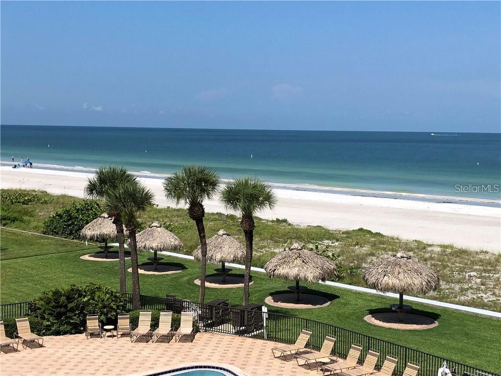 An elevated view of a beach with palm trees, tiki umbrellas, and a swimming pool — 1460 GULF BOULEVARD UNIT 302, CLEARWATER, FL