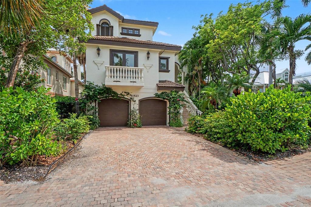 A two-story house with a brick driveway, two garage doors, and a second-floor balcony — 11523 ANDY ROSSE LANE, CAPTIVA, FL