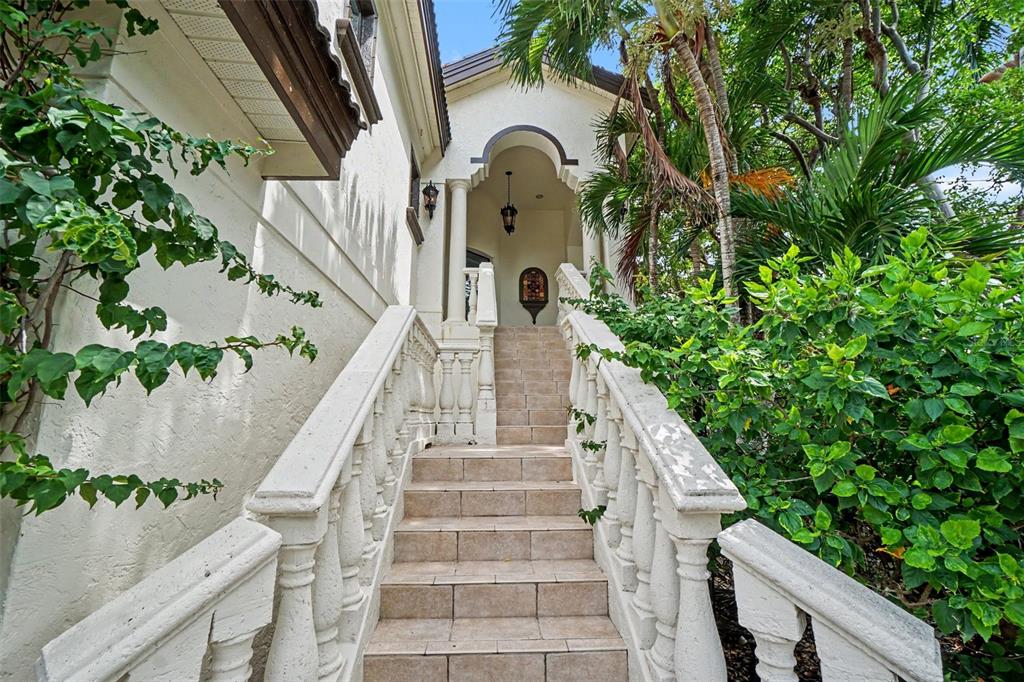 A stone staircase with balustrade railings leads to an arched entryway of a stucco house — 11523 ANDY ROSSE LANE, CAPTIVA, FL