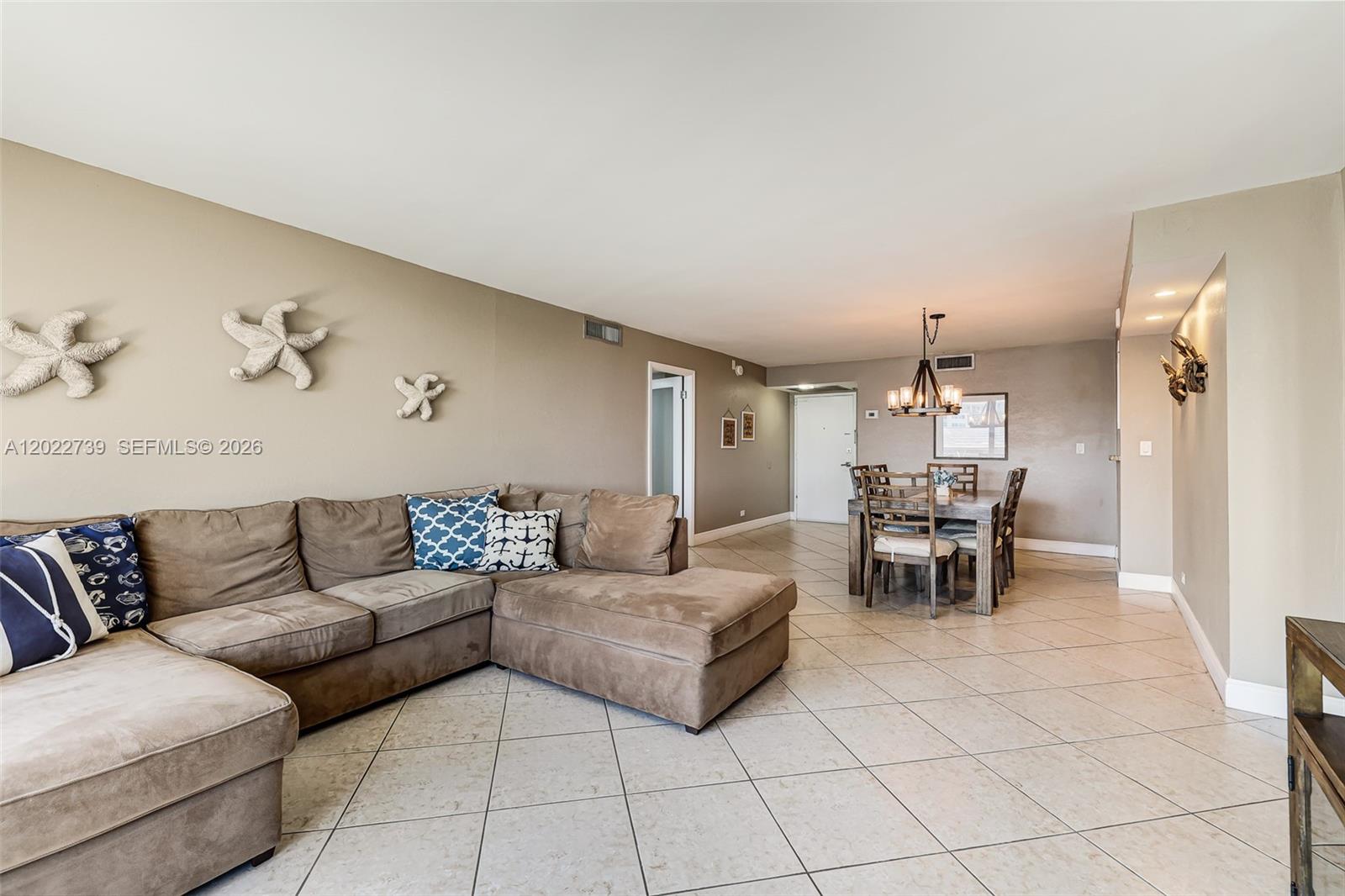 A living and dining area features a brown sectional sofa, tile flooring, and coastal decor — 6039 Collins Ave # 936, Miami Beach FL 33140, MIAMI BEACH, FL