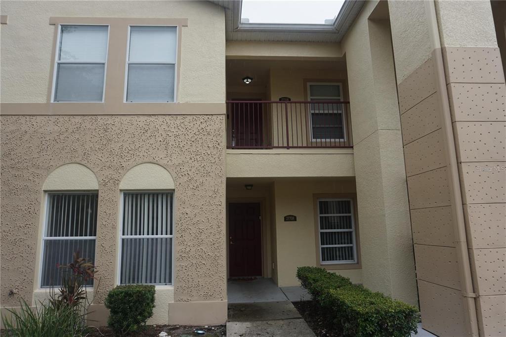 The exterior of a two-story stucco building features a balcony and a ground-level entrance — 2770 CLUB CORTILE CIRCLE UNIT A, KISSIMMEE, FL