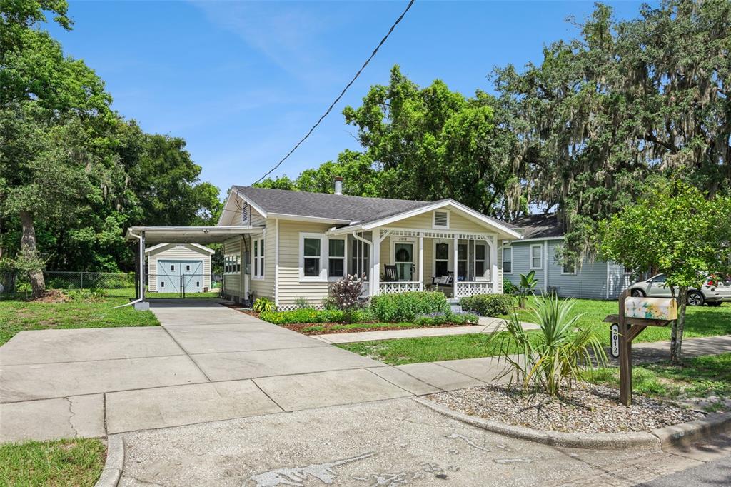 A light yellow single-story house with a front porch, carport, and detached garage — 2012 S PALMETTO AVENUE, SANFORD, FL