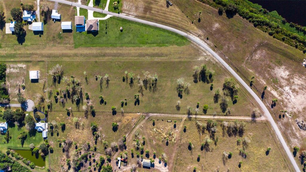 An aerial view shows a large, grassy lot with scattered trees and nearby residential houses — SW 144TH PARKWAY, OKEECHOBEE, FL