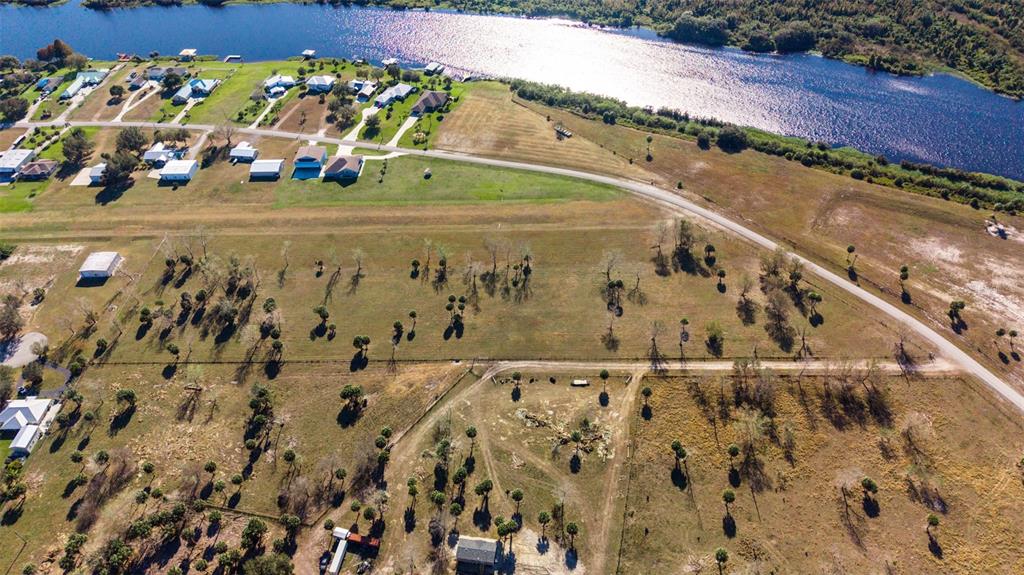 An aerial view shows a large, grassy rural lot near a river and residential houses — SW 144TH PARKWAY, OKEECHOBEE, FL