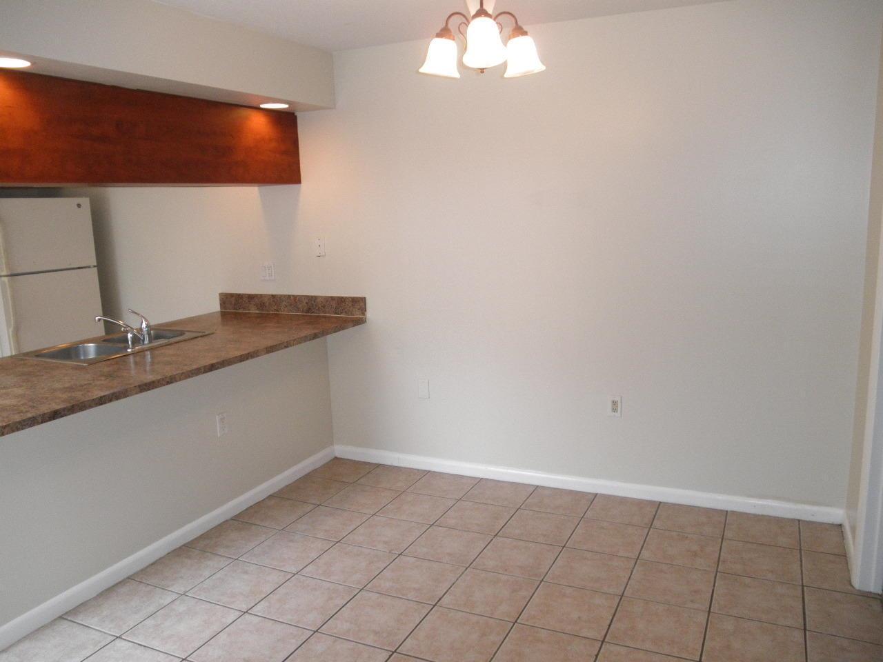 A dining area with tile flooring, a light fixture, and a kitchen breakfast bar — WEST PALM BEACH, FL