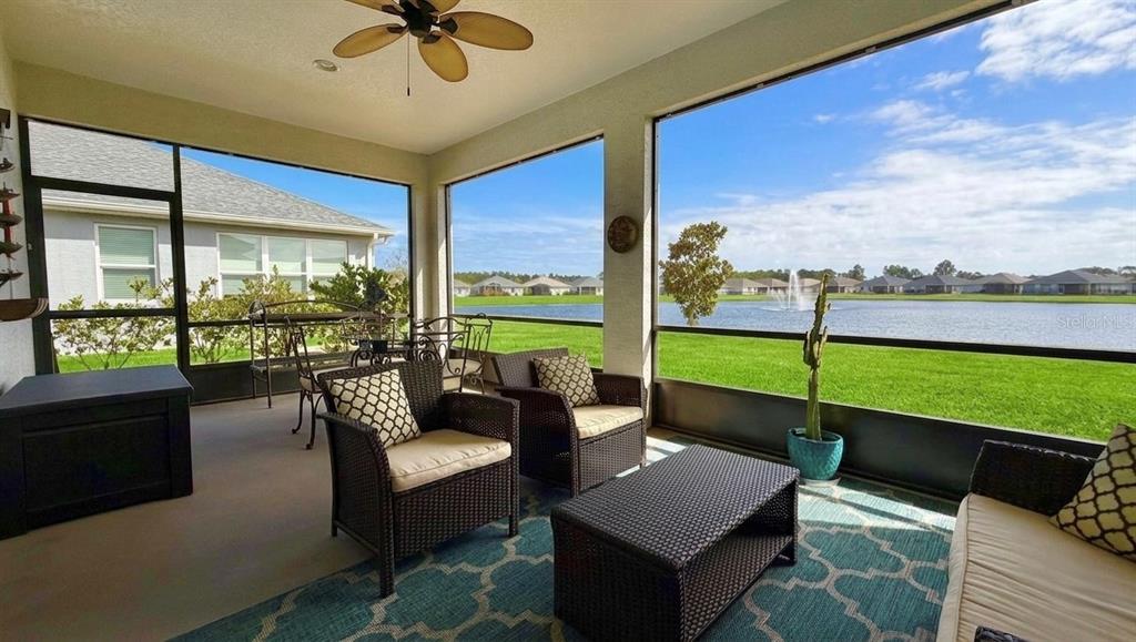 A screened-in patio features wicker furniture, a patterned rug, and a view of a lake — 36 MATANZAS LAKES DRIVE, PALM COAST, FL