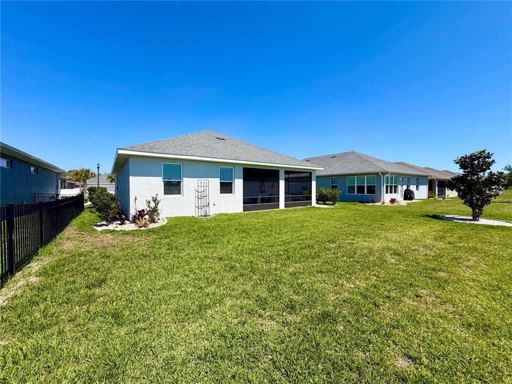 The rear exterior of a single-story house features a screened-in lanai and a fenced yard — 36 MATANZAS LAKES DRIVE, PALM COAST, FL
