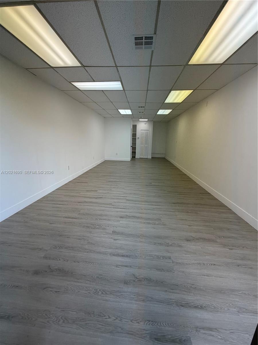 An empty, rectangular office space features light wood-look flooring, white walls, and a drop ceiling — 517 SW 12th Ave, Miami FL 33130, MIAMI, FL