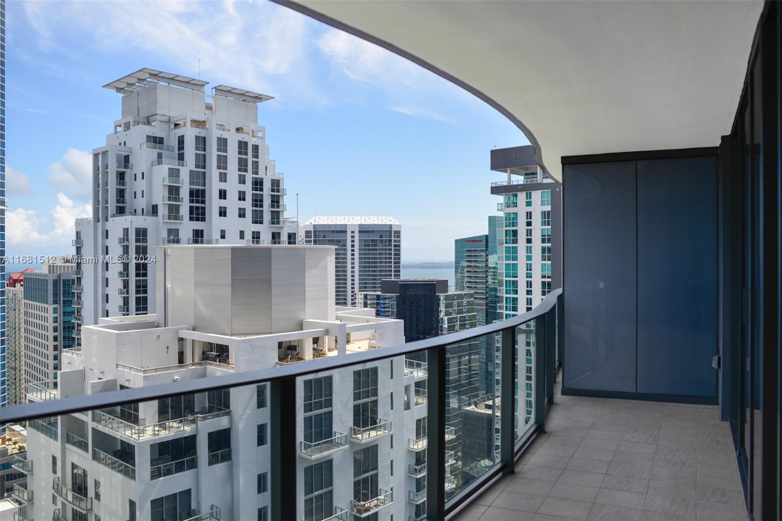 A high-rise balcony with a glass railing overlooks a dense urban cityscape and water — 1000 Brickell Plaza # 3307, Miami FL 33131, MIAMI, FL