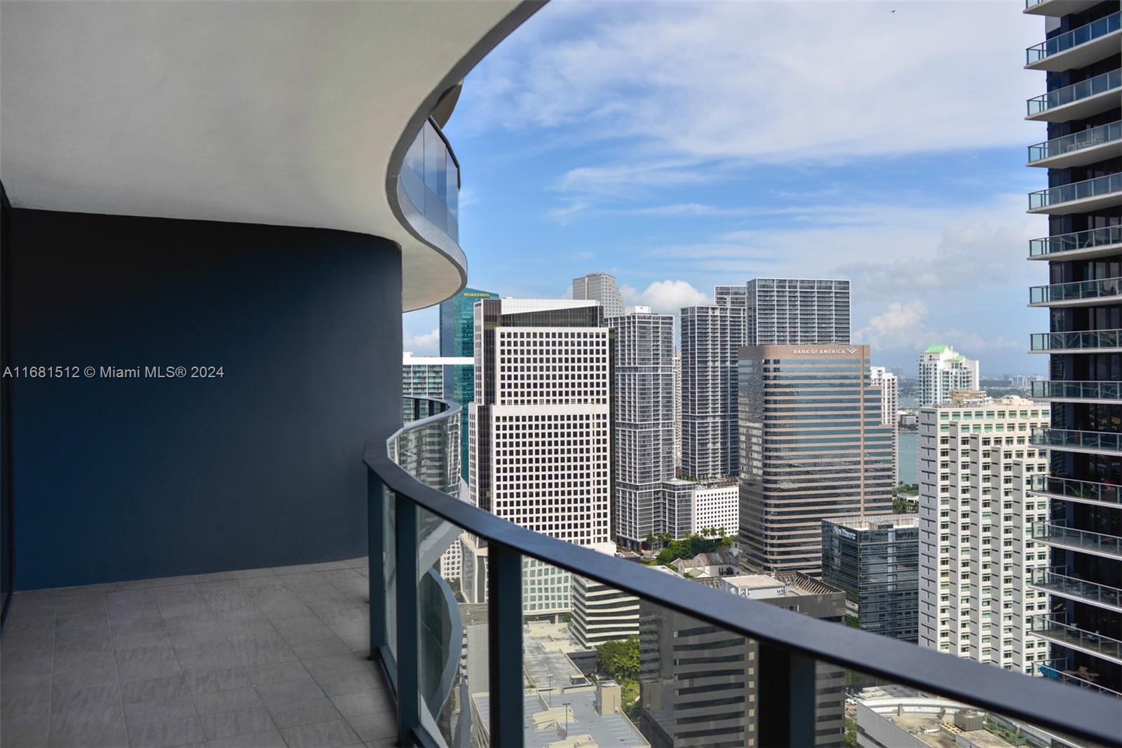A curved balcony with a glass railing overlooks a dense city skyline — 1000 Brickell Plaza # 3307, Miami FL 33131, MIAMI, FL