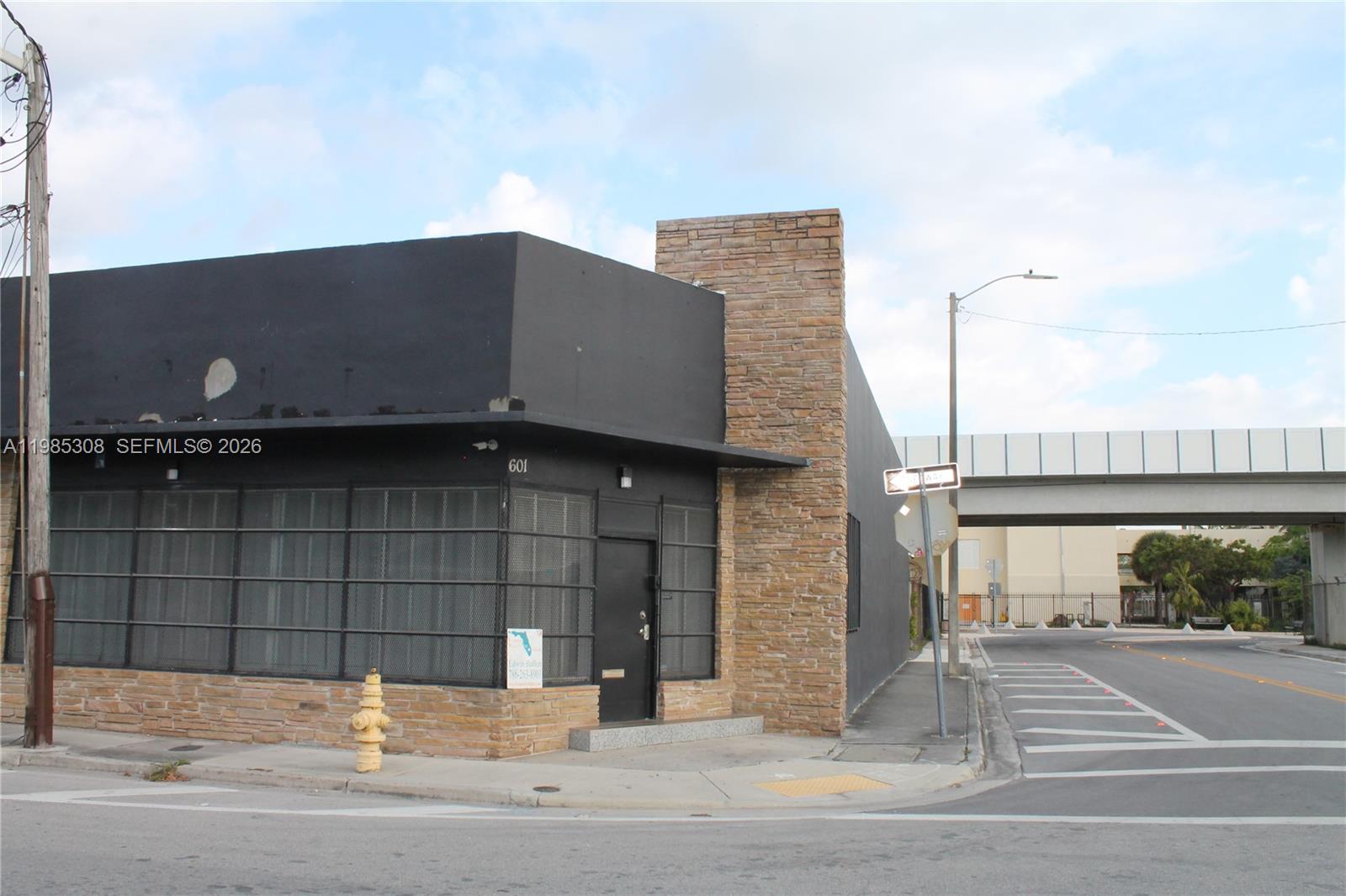 A single-story commercial building with black walls, stone accents, and a corner entrance — 601 NW 11th St, Miami FL 33136, MIAMI, FL
