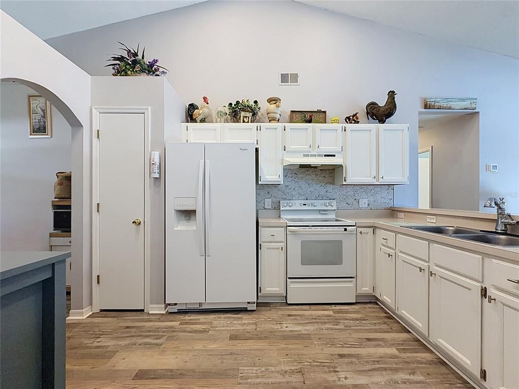 A kitchen with white cabinets, white appliances, and wood-look flooring under a vaulted ceiling — 336 CALIFORNIA BOULEVARD, DAVENPORT, FL