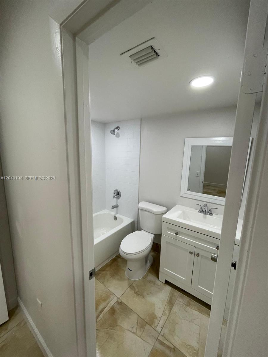 A small bathroom features a white vanity, a toilet, and a shower-tub combination — 13037 SW 88th Ln # 204A, Miami FL 33186, MIAMI, FL