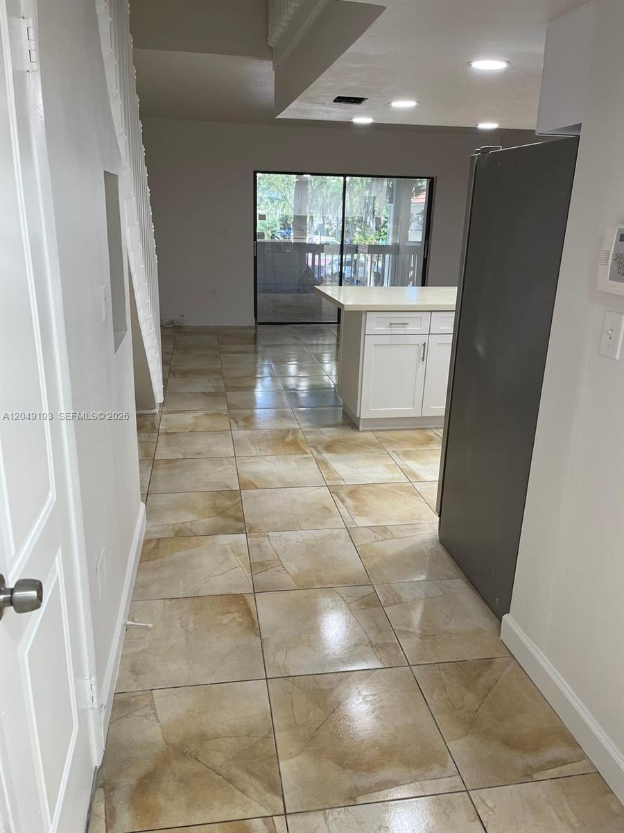 A tiled kitchen area features a white island and a sliding glass door — 13037 SW 88th Ln # 204A, Miami FL 33186, MIAMI, FL