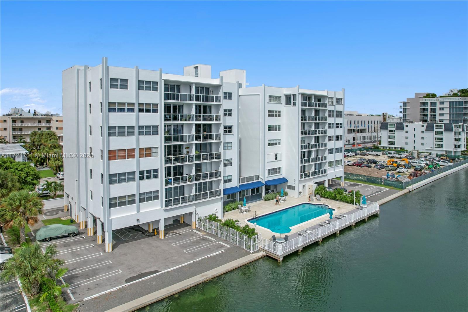 An aerial view shows a white multi-story apartment building with a pool beside a canal — 9381 E Bay Harbor Dr # 401N, Bay Harbor Islands FL 33154, BAY HARBOR ISLANDS, FL