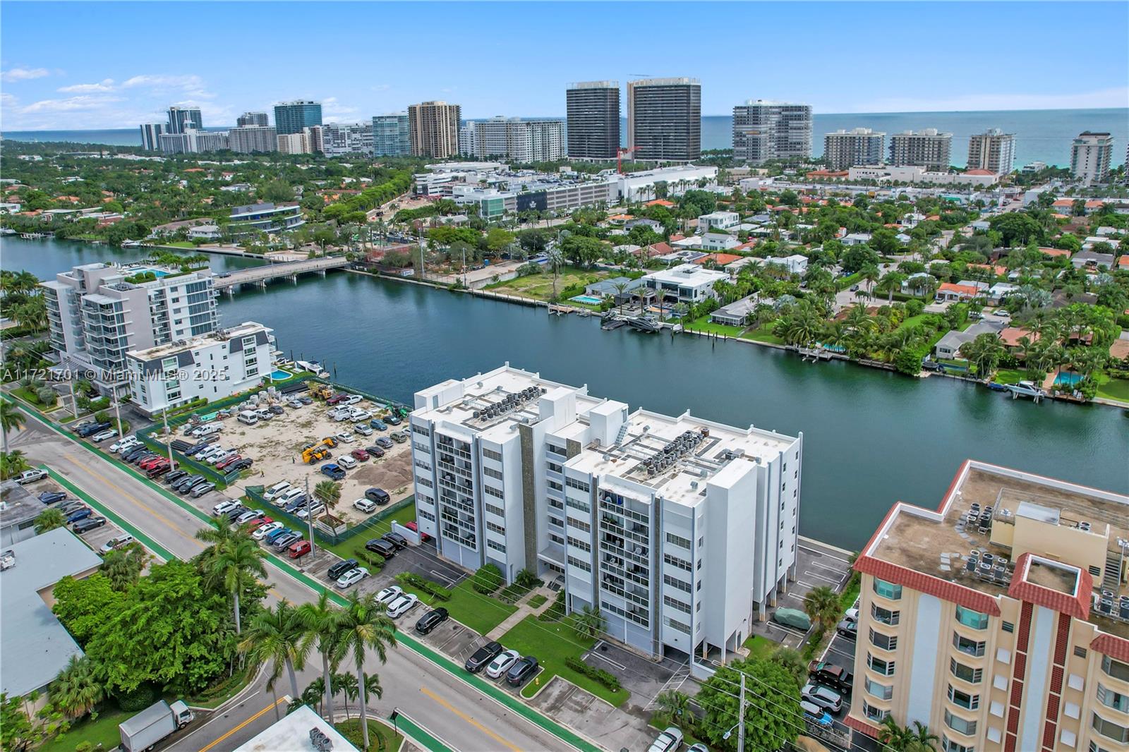 An aerial view shows a white apartment building near a canal with a city skyline — 9381 E Bay Harbor Dr # 401N, Bay Harbor Islands FL 33154, BAY HARBOR ISLANDS, FL
