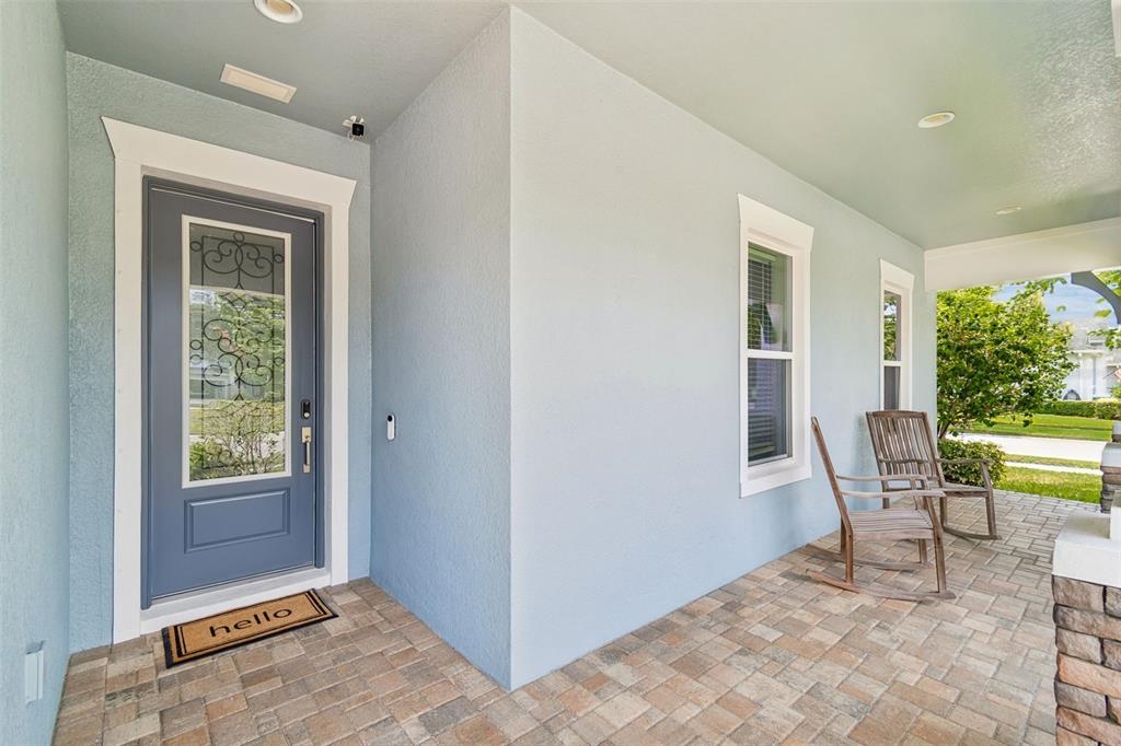 A covered front porch with light blue walls, a gray front door, and two rocking chairs — 4000 BLUE LANTANA LANE, LAND O LAKES, FL