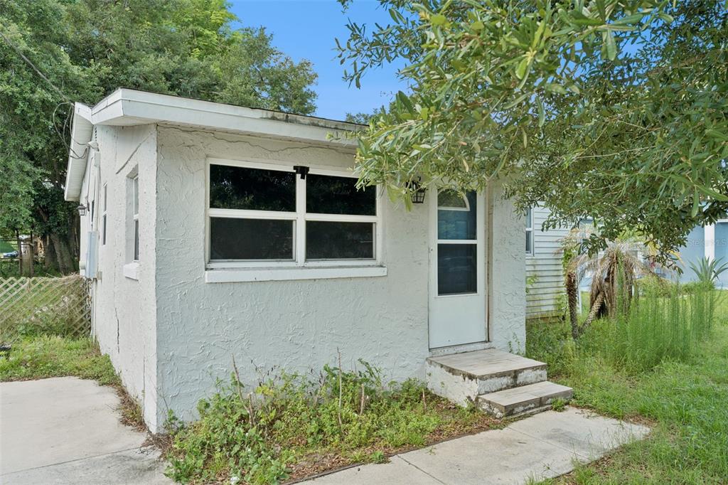 A small, white, stucco-sided house with a single door and a large window — 5000 HUPPEL AVENUE, ORLANDO, FL