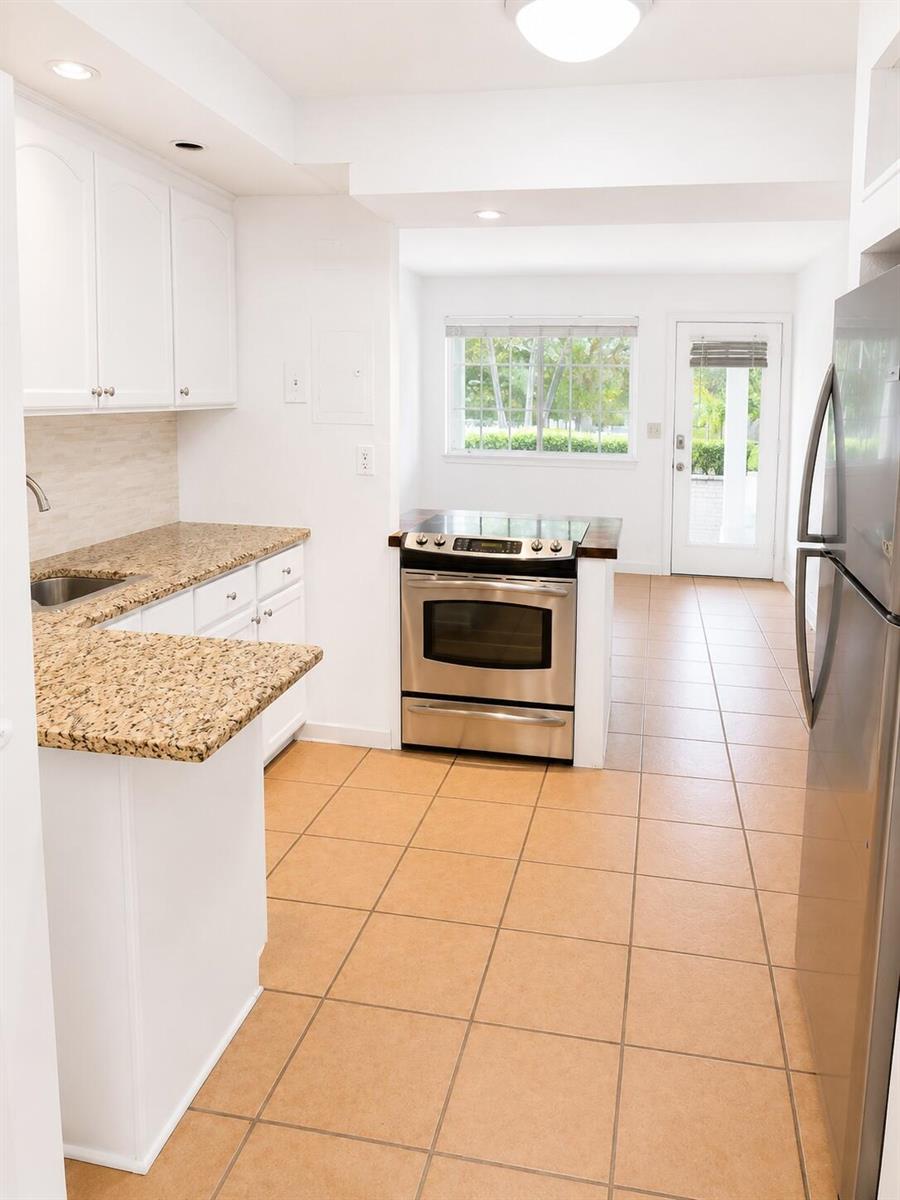 A kitchen with white cabinets, granite countertops, stainless steel appliances, and tan tile flooring — 3115 Park Avenue # 3, Singer Island FL 33404, SINGER ISLAND, FL