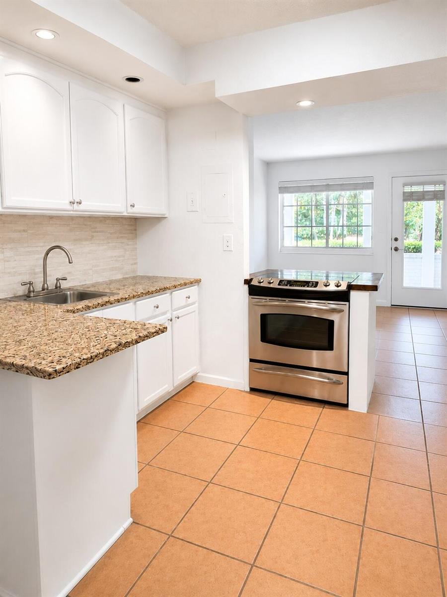 A kitchen features white cabinets, granite countertops, a stainless steel oven, and tan tile flooring — 3115 Park Avenue # 3, Singer Island FL 33404, SINGER ISLAND, FL