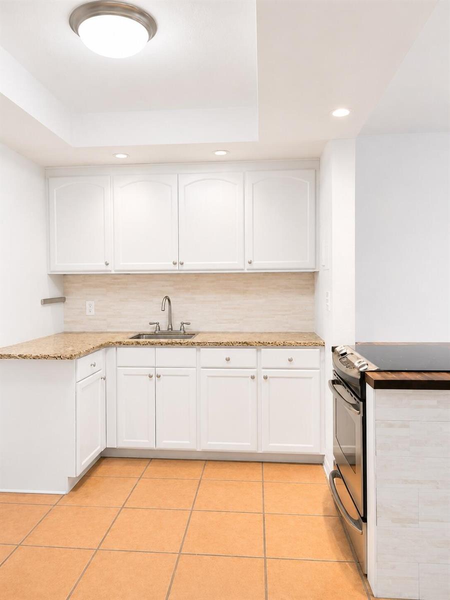 A kitchen features white cabinets, granite countertops, a stainless steel sink, and orange tile flooring — 3115 Park Avenue # 3, Singer Island FL 33404, SINGER ISLAND, FL