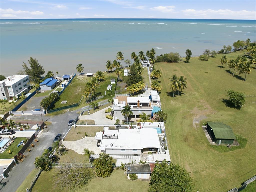 An aerial view shows several coastal houses with swimming pools situated on a grassy lot — Pr 968k 2.1 int Punta Are LAS PICUAS, RIO GRANDE, PR