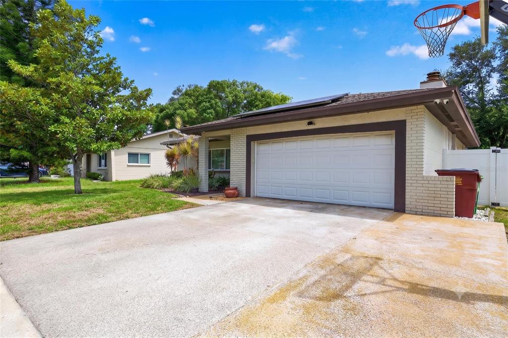 A single-story house with a white brick exterior, a two-car garage, and a concrete driveway — 1977 CITRUS HILL ROAD, PALM HARBOR, FL