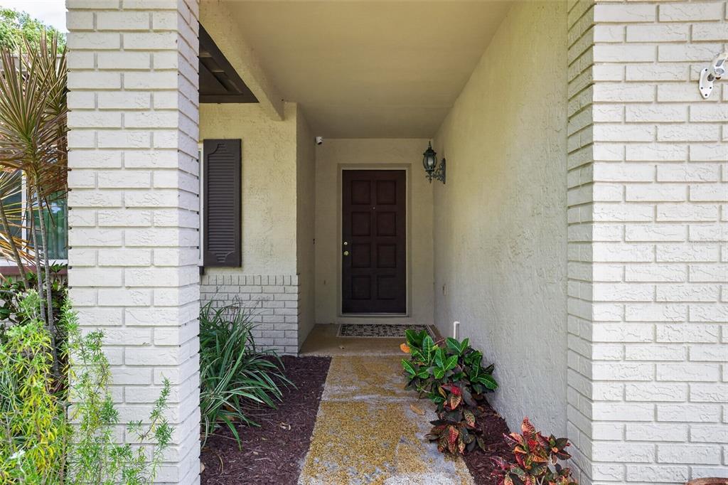 A covered entryway features a dark brown front door flanked by white painted brick pillars — 1977 CITRUS HILL ROAD, PALM HARBOR, FL