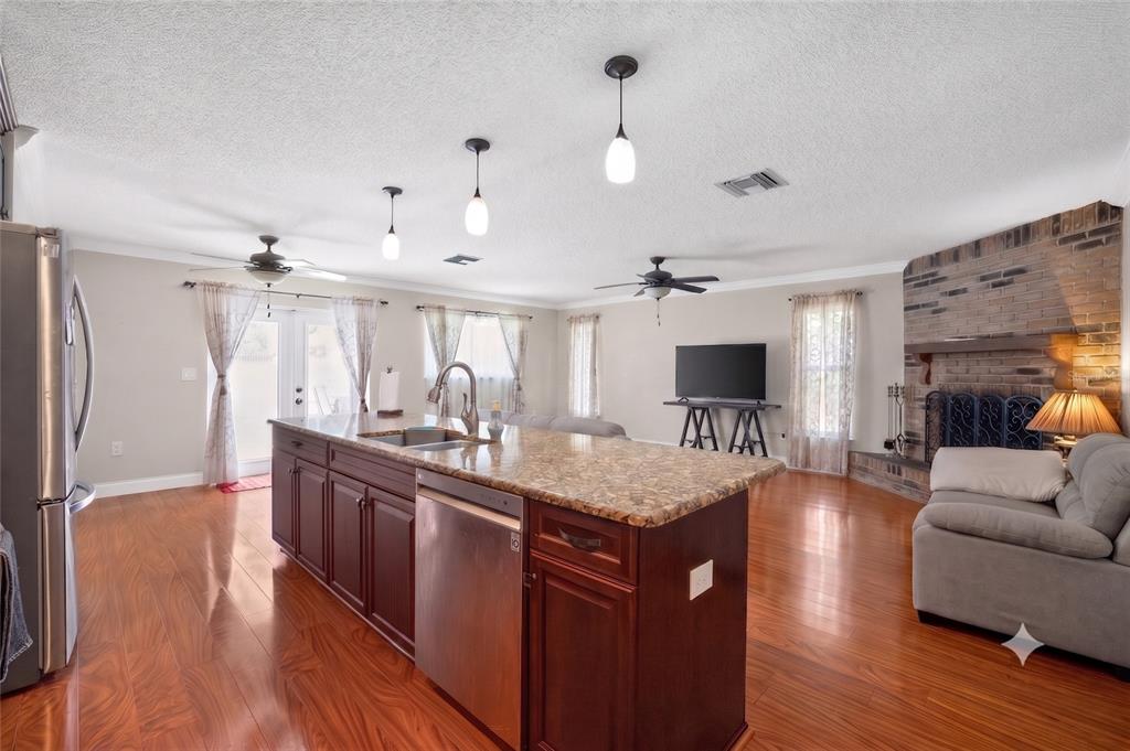 A kitchen with a granite-topped island and dark wood cabinets opens into a living area — 1977 CITRUS HILL ROAD, PALM HARBOR, FL