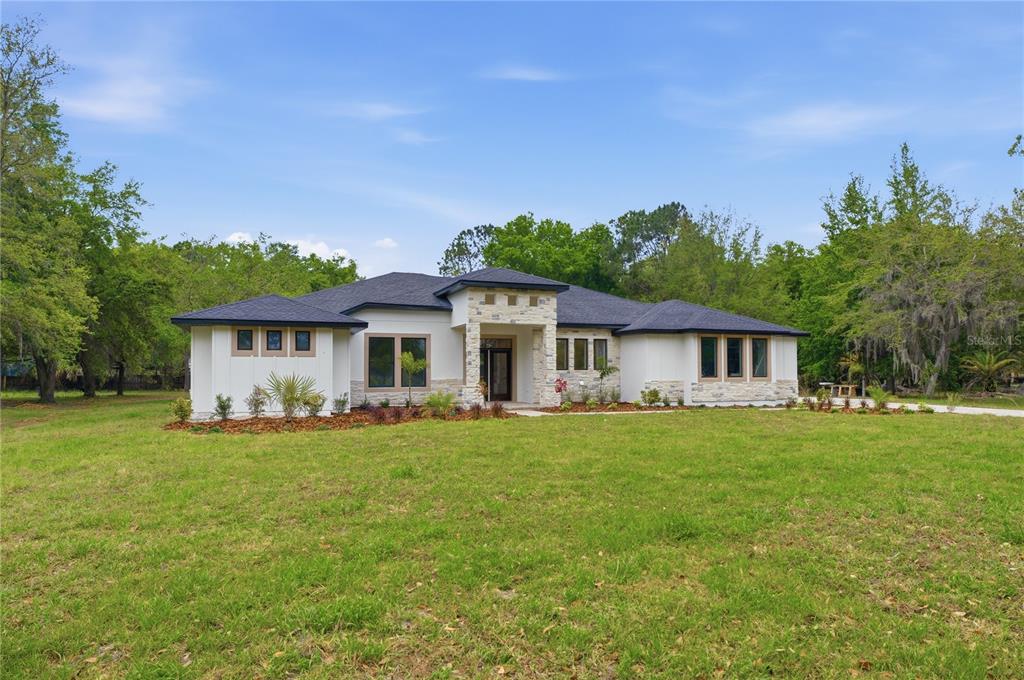 A modern single-story house with a stone facade and a dark hip roof — 1516 PINE ISLAND ROAD, KISSIMMEE, FL