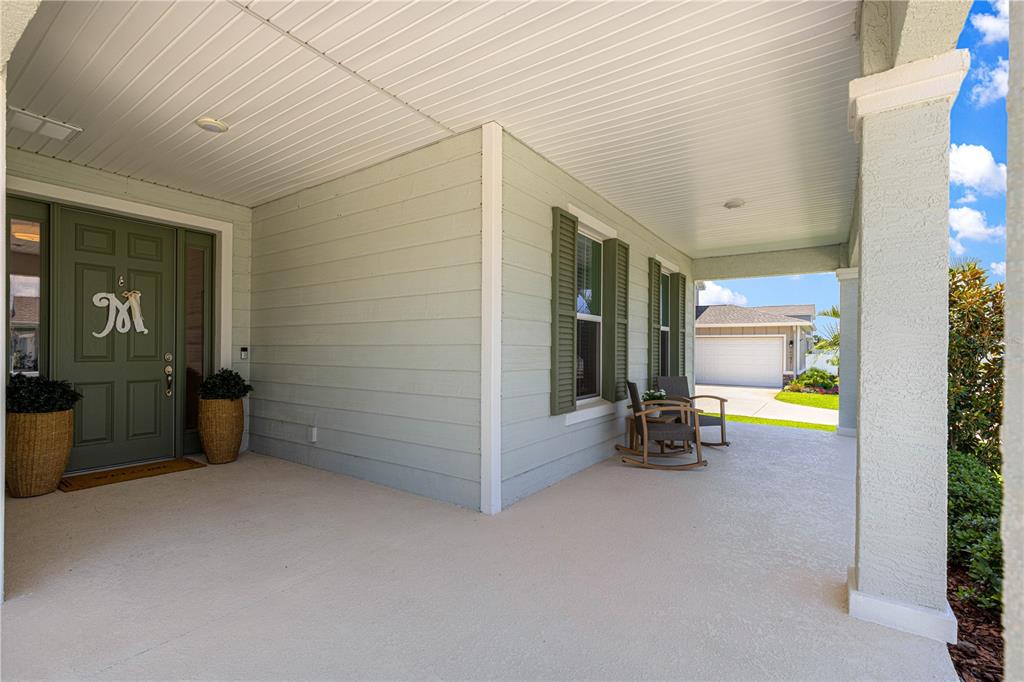 A covered front porch features light green siding, a dark green front door, and rocking chairs — 6237 SW 71ST TERRACE ROAD, OCALA, FL