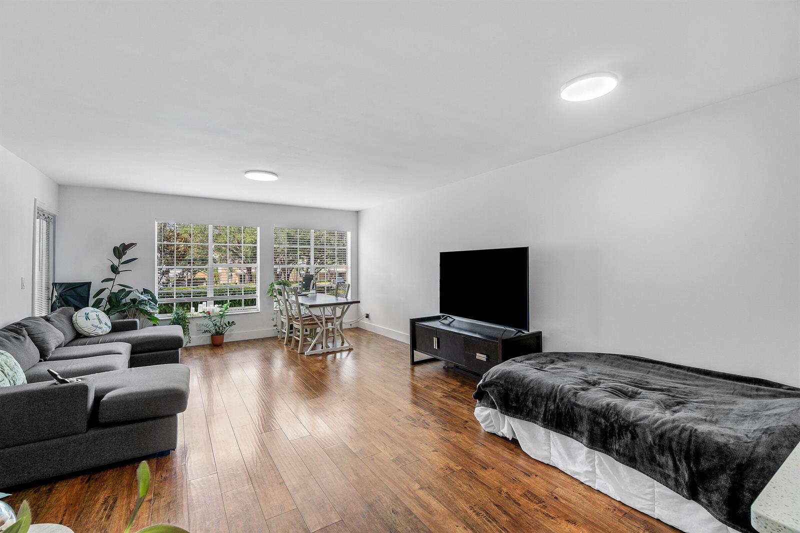 A living room features hardwood floors, a gray sectional sofa, a television, and a bed — 6283 La Costa Drive, Boca Raton FL 33433, BOCA RATON, FL