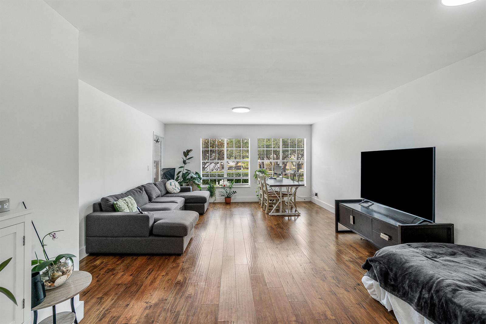 A living room features hardwood floors, a gray sectional sofa, a dining set, and television — 6283 La Costa Drive, Boca Raton FL 33433, BOCA RATON, FL