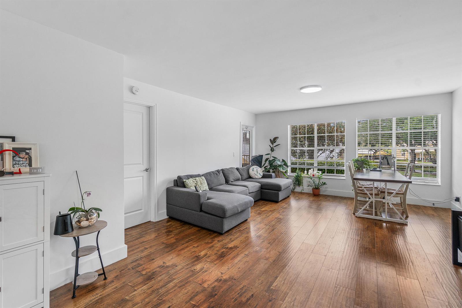 A living and dining area features white walls, dark wood flooring, and a gray sectional sofa — 6283 La Costa Drive, Boca Raton FL 33433, BOCA RATON, FL