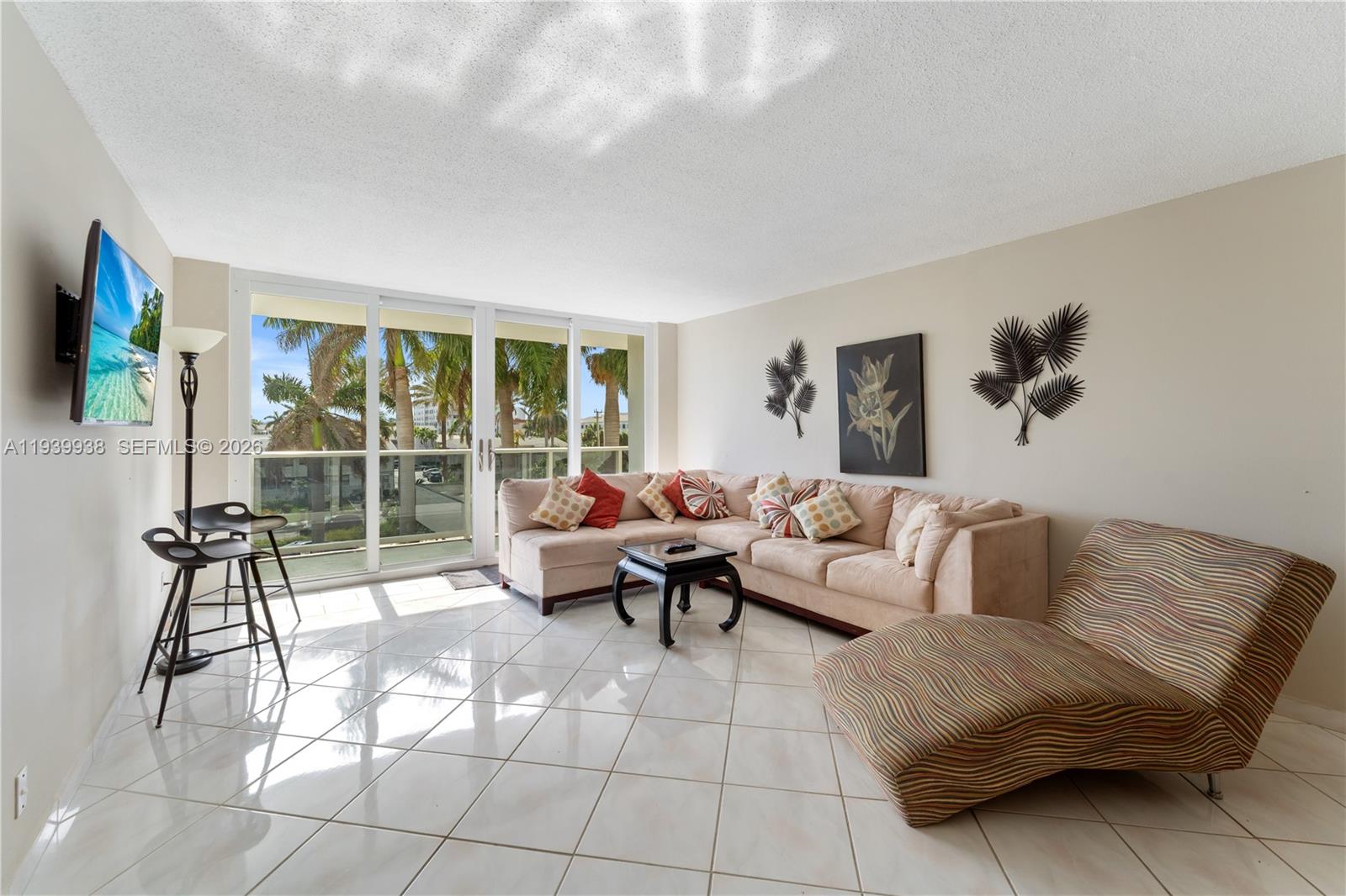 A living room features a beige sectional sofa, a patterned chaise lounge, and tile flooring — 3140 S Ocean Dr # 212, Hallandale Beach FL 33009, HALLANDALE BEACH, FL