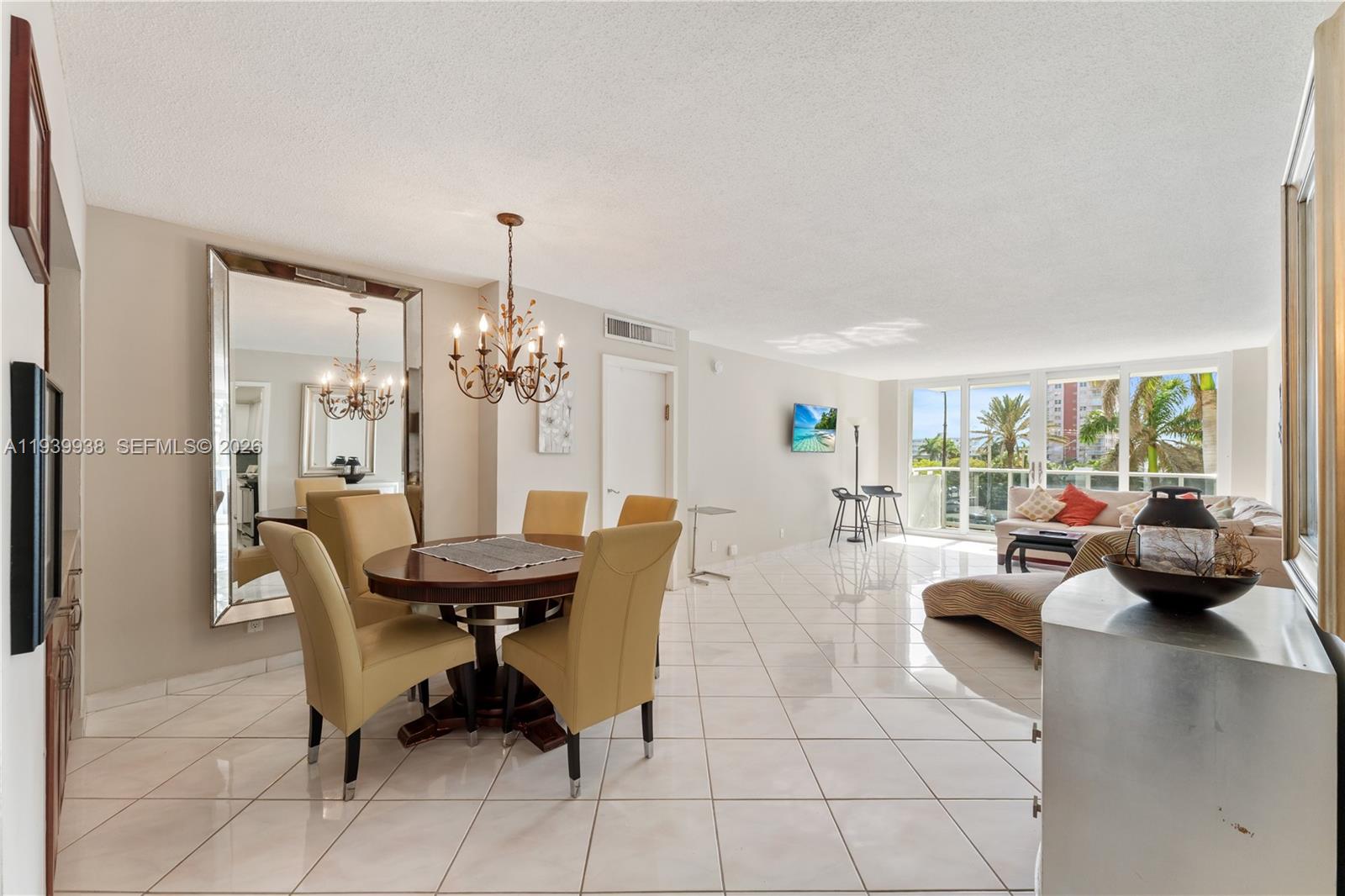 A dining area with a round table and chandelier opens into a living room — 3140 S Ocean Dr # 212, Hallandale Beach FL 33009, HALLANDALE BEACH, FL