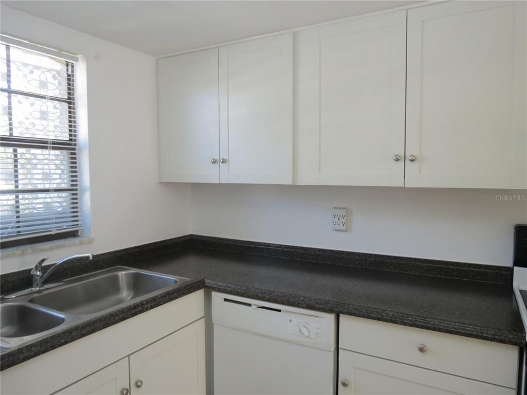 A kitchen features white cabinets, a dark countertop, a stainless steel sink, and a dishwasher — 625 N HALIFAX AVENUE UNIT 6, DAYTONA BEACH, FL