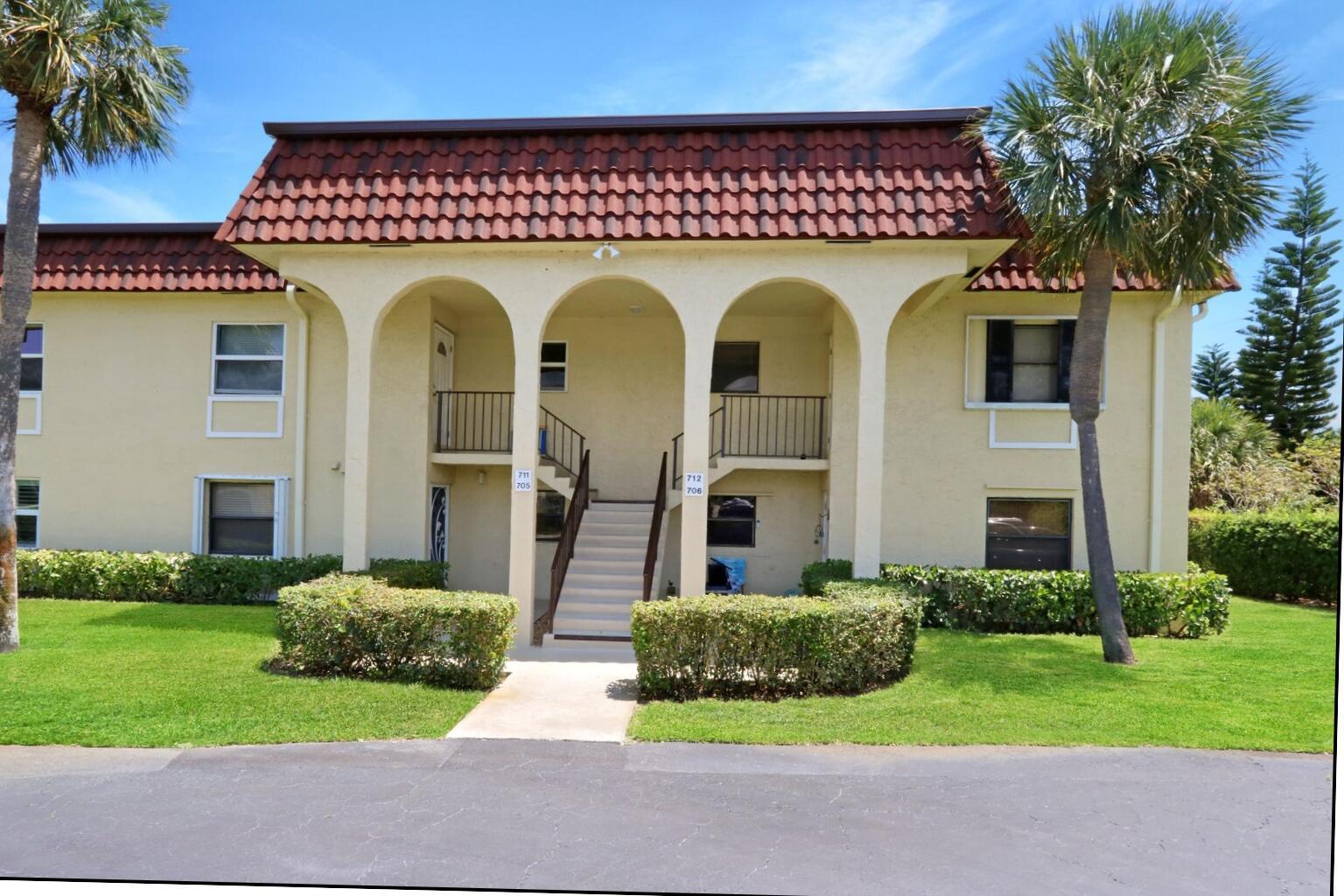 A two-story apartment building with a red tile roof, arched entryway, and central exterior staircase — 717 S Us Hwy 1 # 712, Jupiter FL 33477, JUPITER, FL