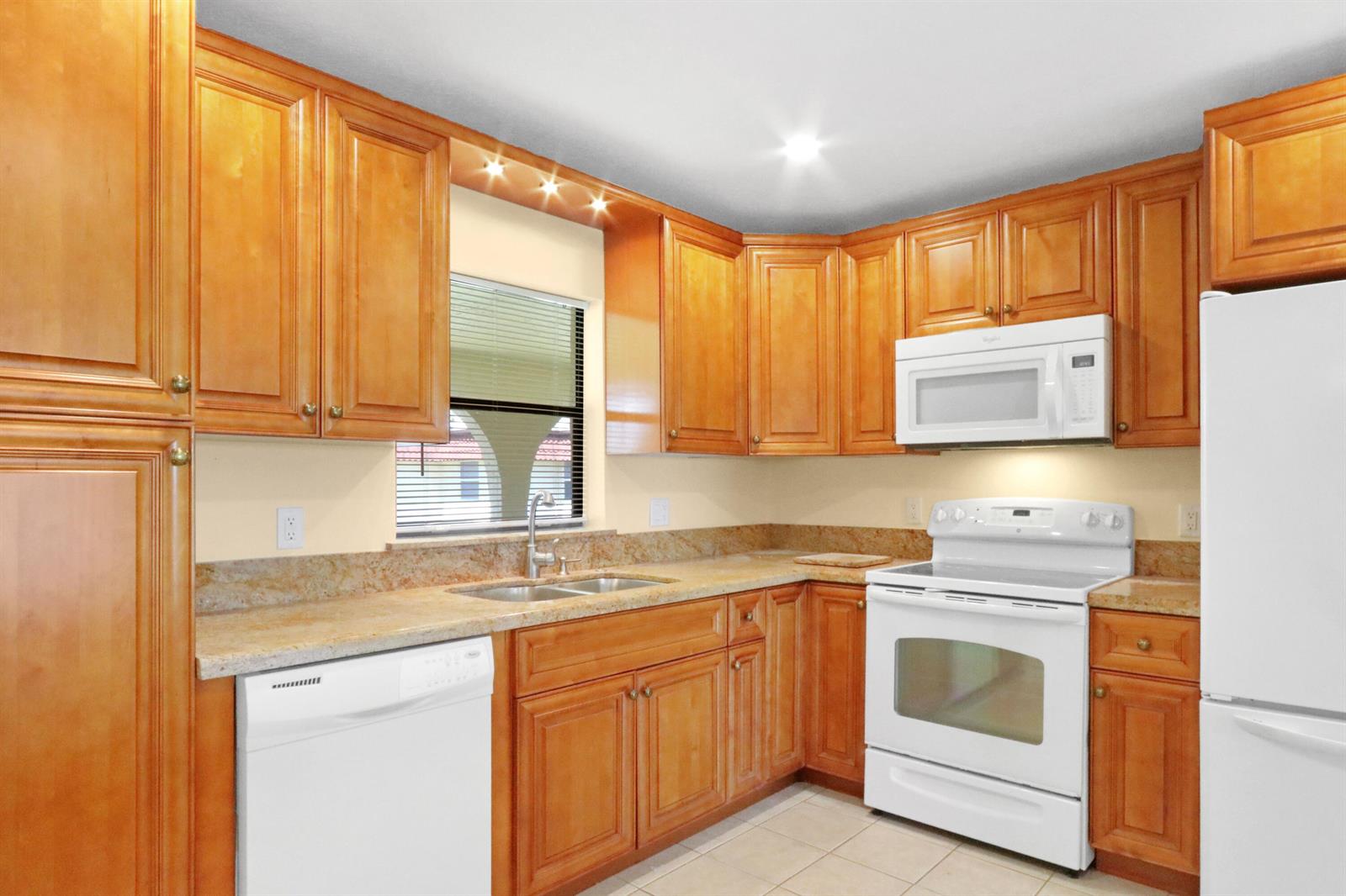 A kitchen features light wood cabinets, granite countertops, white appliances, and a window above the sink — 717 S Us Hwy 1 # 712, Jupiter FL 33477, JUPITER, FL