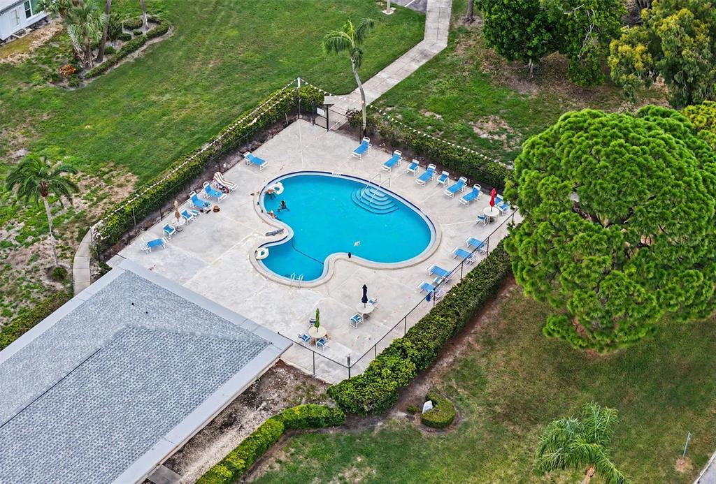 An aerial view shows a kidney-shaped swimming pool surrounded by lounge chairs and a fence — 8359 CANDLEWOOD ROAD UNIT 8359, SEMINOLE, FL