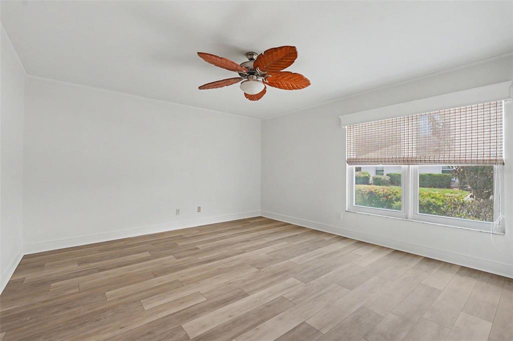 An empty bedroom features white walls, light wood-look flooring, and a palm-leaf ceiling fan — 8359 CANDLEWOOD ROAD UNIT 8359, SEMINOLE, FL