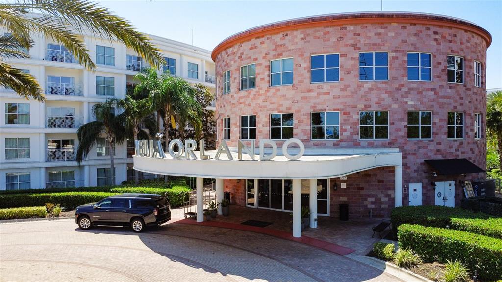 A circular brick building with a white porte-cochère entrance and a parked black SUV — 225 CELEBRATION PLACE UNIT 316, KISSIMMEE, FL