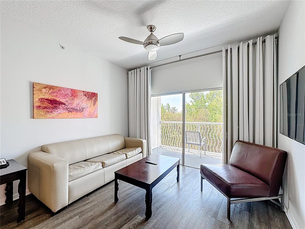 A living room features a beige sofa, a dark wood coffee table, and a leather chair — 225 CELEBRATION PLACE UNIT 316, KISSIMMEE, FL