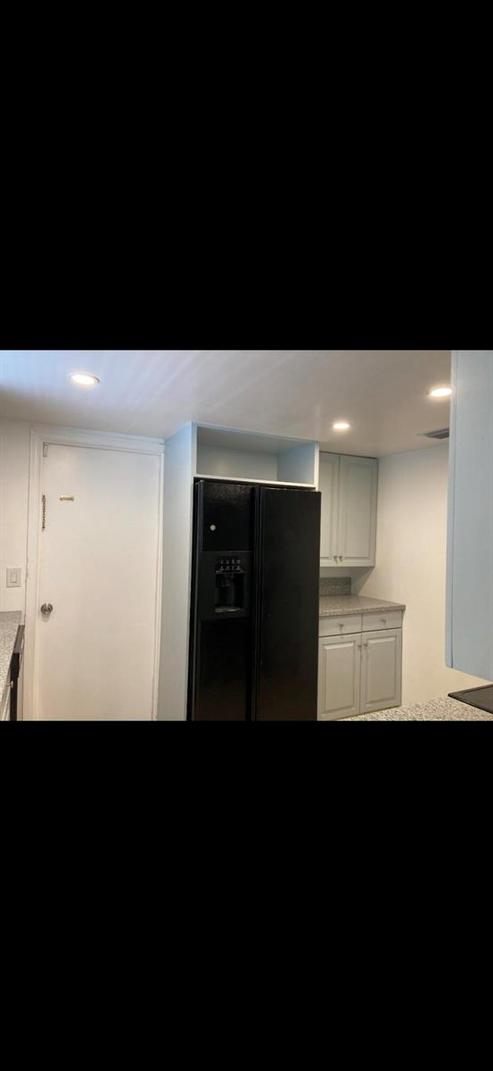 A kitchen features a black refrigerator, light gray cabinets, and speckled granite countertops — 1243 Kinglet Terrace, Wellington FL 33414, WELLINGTON, FL